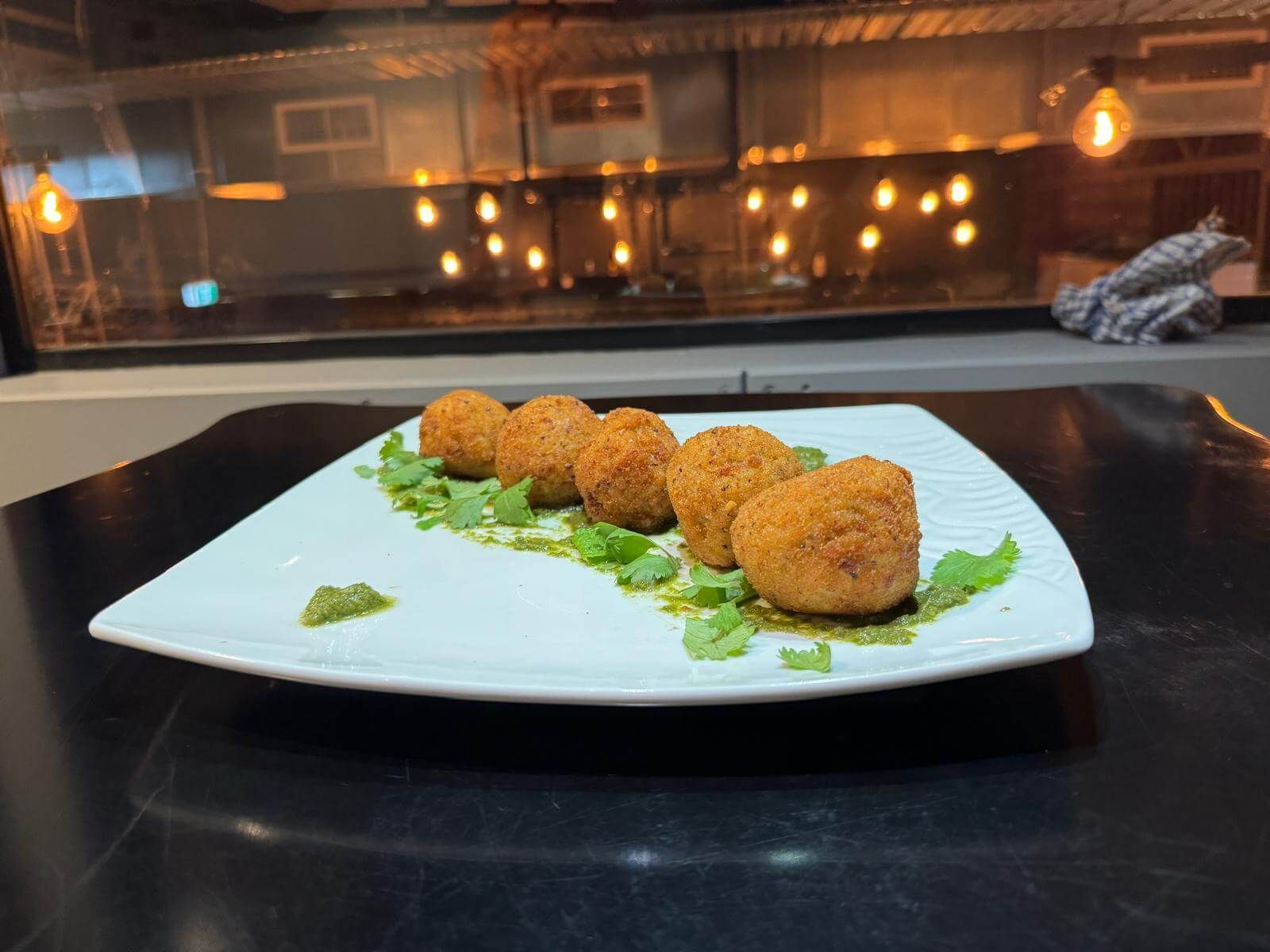 Golden fried arancini on a white plate with fresh greens