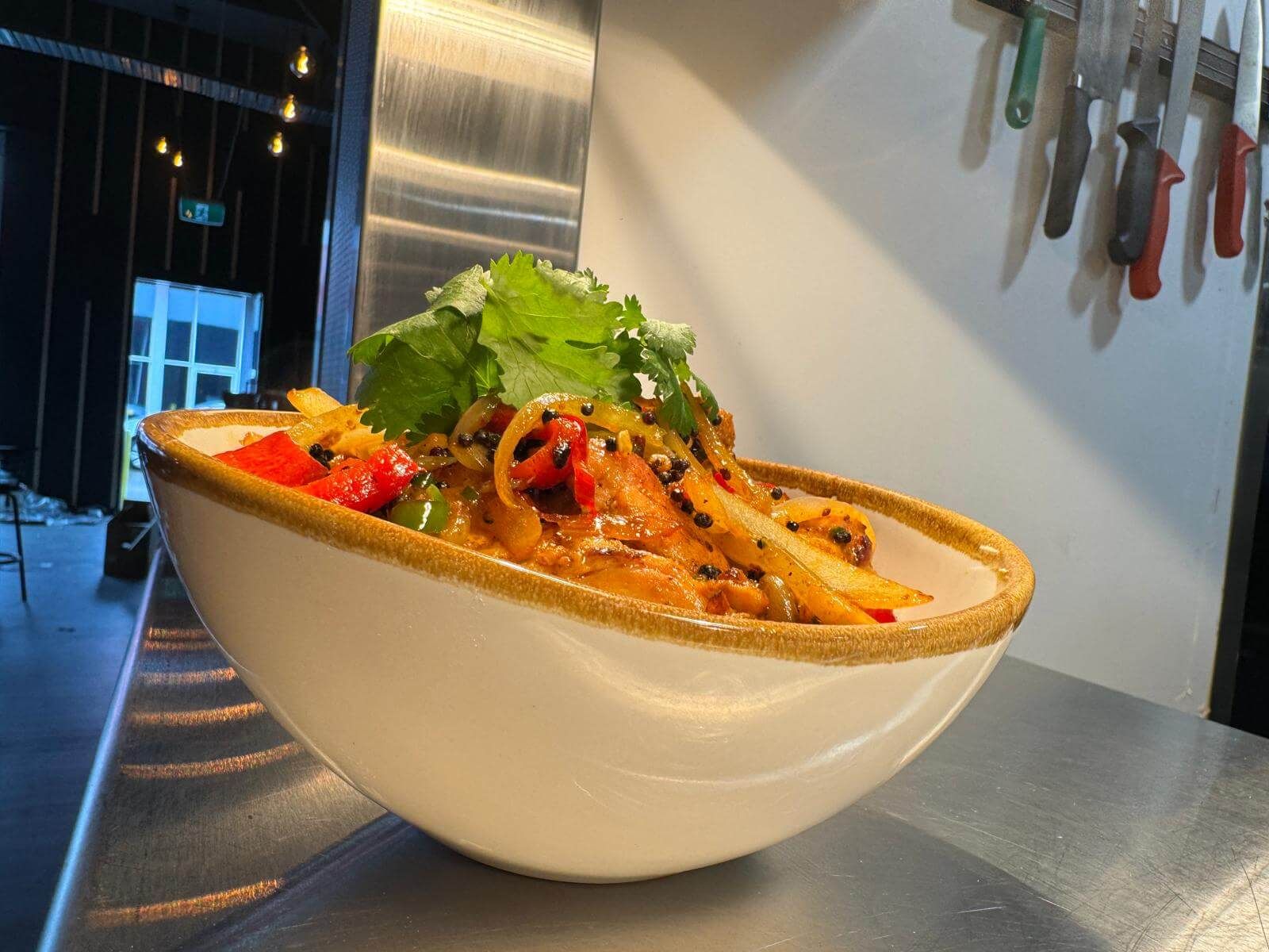Stir-fried noodles in a white bowl on the kitchen pass